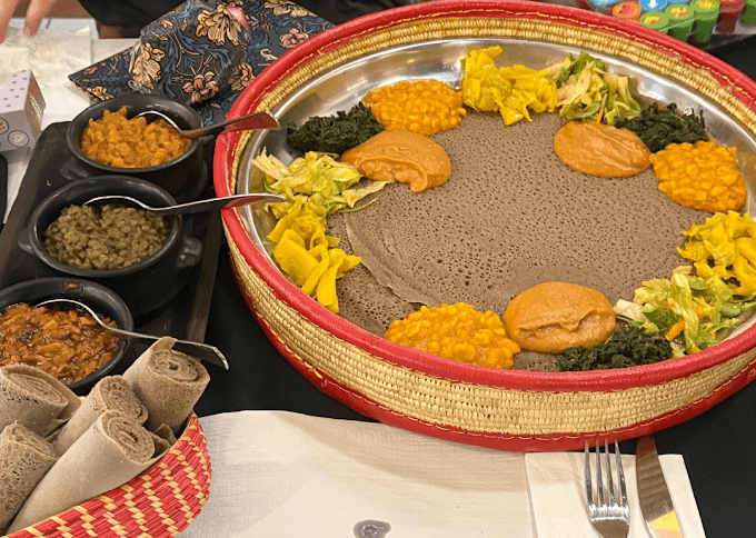 Vegetarian injera platter with lentils, vegetables, traditional Ethiopian stews, and homemade East African specialties in Neuchâtel