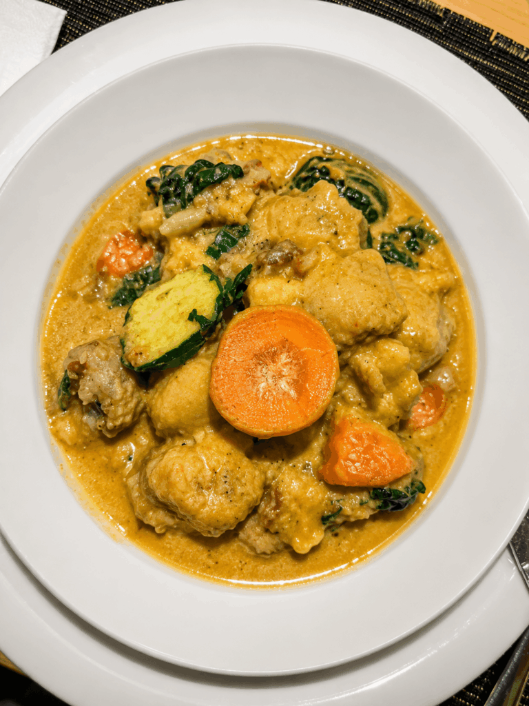 Creamy African vegetable and chicken stew prepared with traditional East African spices at African Queen restaurant in Zürich