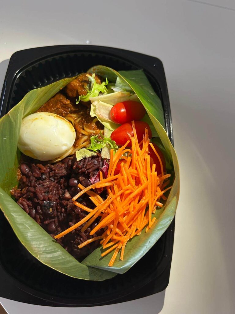 Authentic Ghanaian Waakye meal box with rice and beans, boiled egg, fresh salad, and homemade African sauce prepared by AfroSwiss Cuisine in Geneva