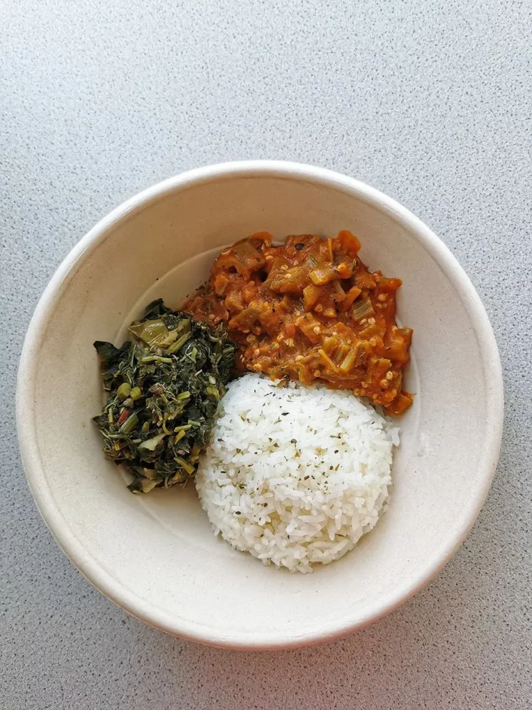 Traditional Congolese rice bowl with okra sauce and African greens at BOMOZIKA Zürich