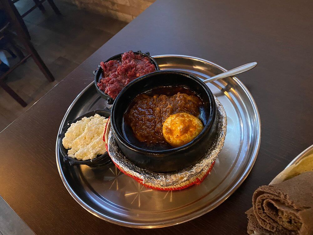 Authentic Eritrean kitfo and spicy meat stew served at Hidmona Geneva