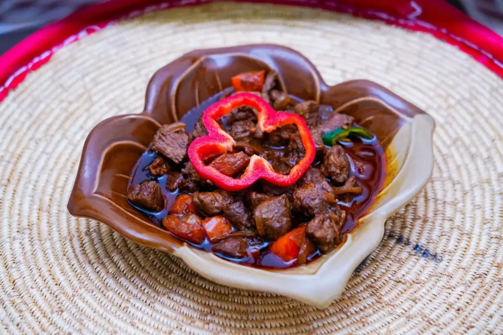 Traditional Ethiopian beef stew served in a clay bowl with spices and fresh red pepper at Ge’ez Restaurant Lausanne