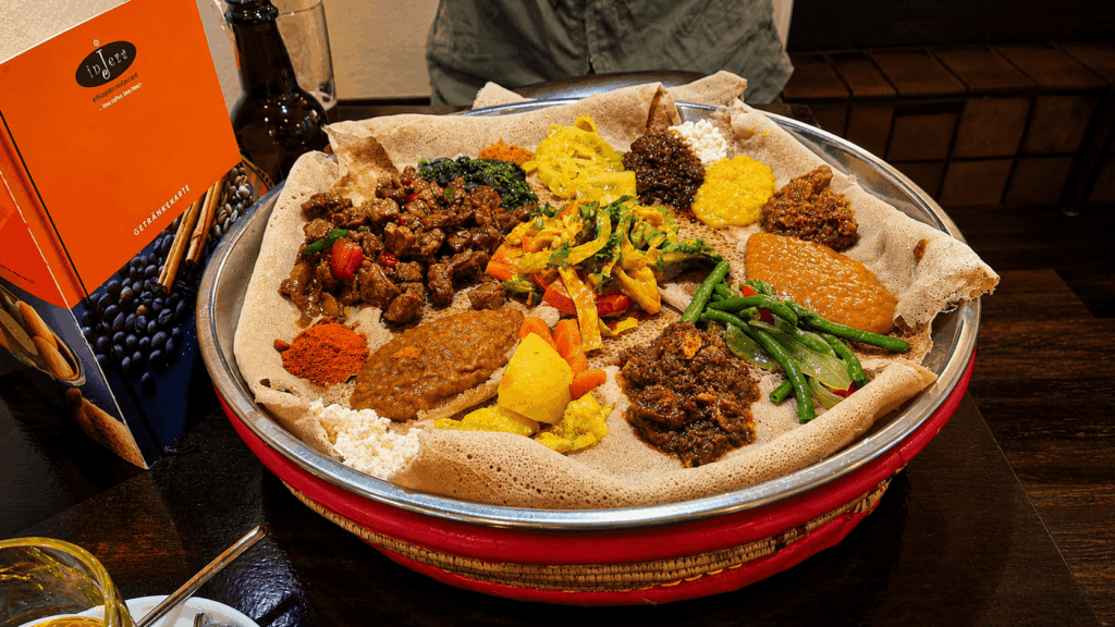 Large Habesha sharing platter with traditional Ethiopian and Eritrean dishes served on injera bread in Bern