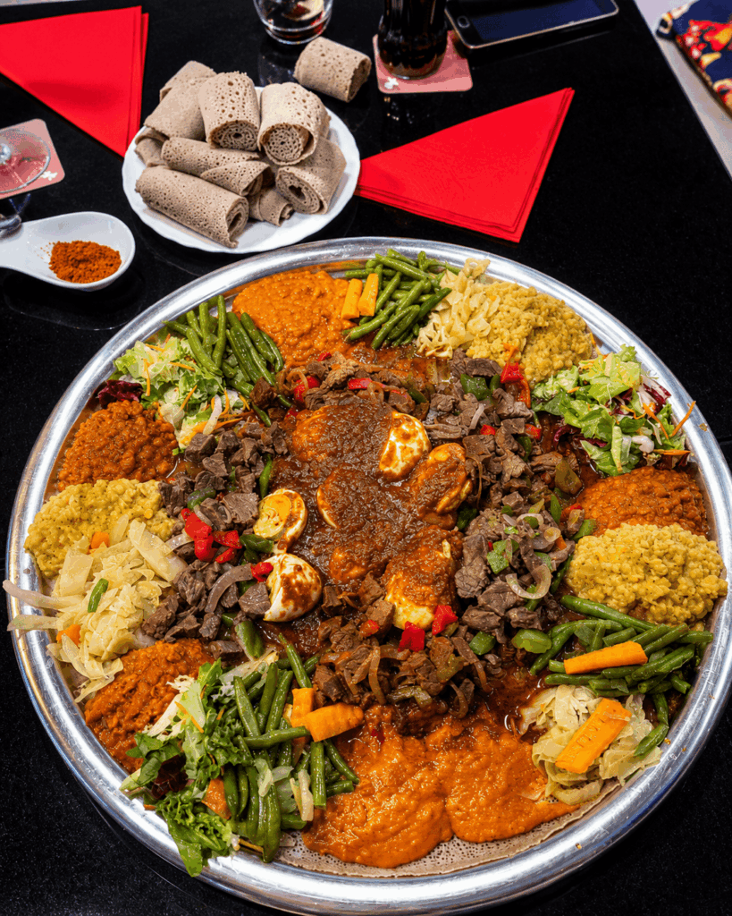 Large Eritrean sharing platter with doro wat, beef dishes, lentils, vegetables, and injera at Helen Eritrean Lounge