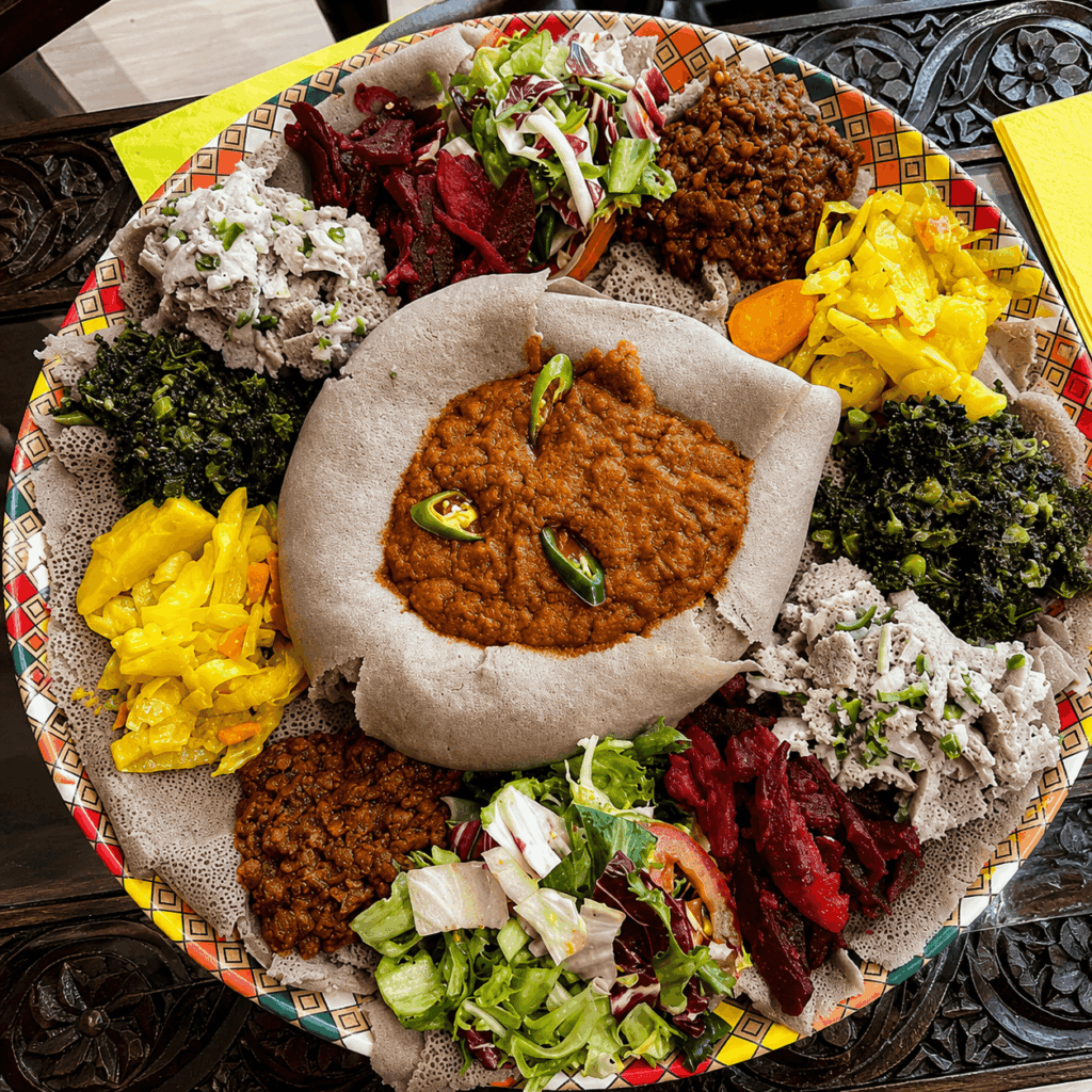 Vegetarian Ethiopian and Eritrean injera platter with lentils, cabbage, spinach, salad, and traditional side dishes at Mercato Restaurant