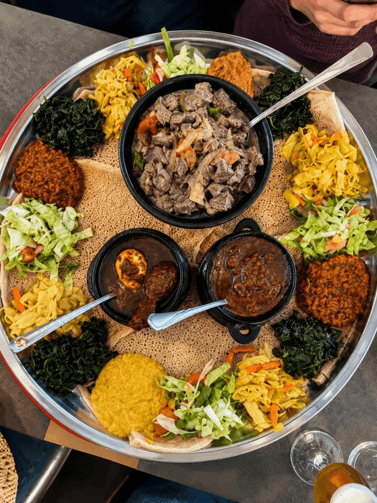 Traditional Ethiopian and Eritrean sharing platter with injera, stews, vegetables, and grilled meat at Mesob restaurant in Zürich