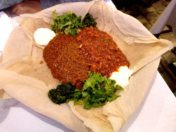 Traditional African family-style sharing dish with injera and East African specialties at Mosaique Geneva