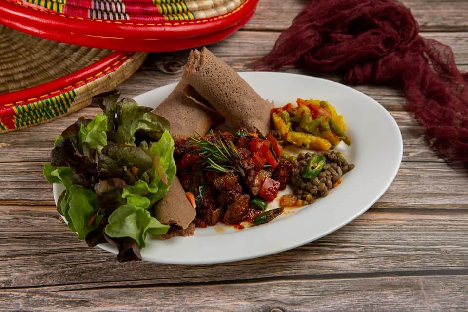 Eritrean grilled beef dish with injera, lentils, and vegetables served at Raena East African restaurant.