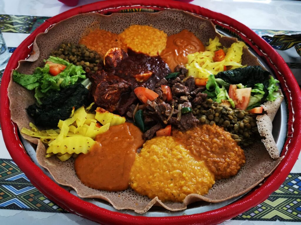 Mixed Ethiopian and Eritrean injera platter with lentils, beef, vegetables, and spicy sauces at Red Sea Restaurant Habesha