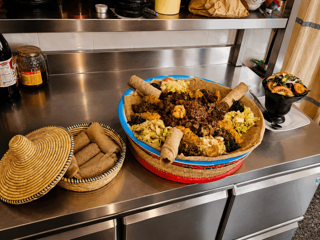 Large African sharing platter with injera, vegetables, meat specialties, and traditional East African flavors at Savanna Restaurant
