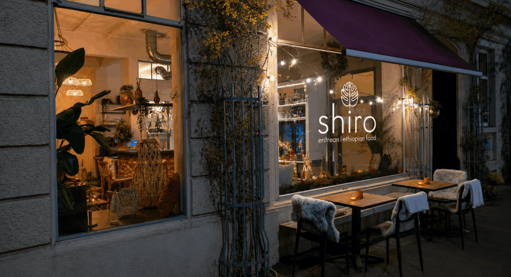 Exterior view of Shiro Basel Ethiopian and Eritrean restaurant in Kleinbasel with inviting terrace seating and warm evening atmosphere