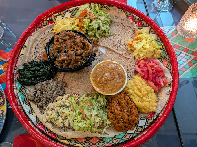 Authentic Ethiopian Shiro stew,tibs with injera bread, lentils, and fresh vegetable accompaniments at Liyu Restaurant
