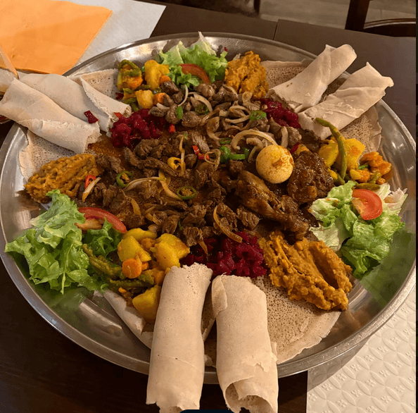 Authentic Eritrean sharing platter with injera and traditional dishes at Hidmona Geneva