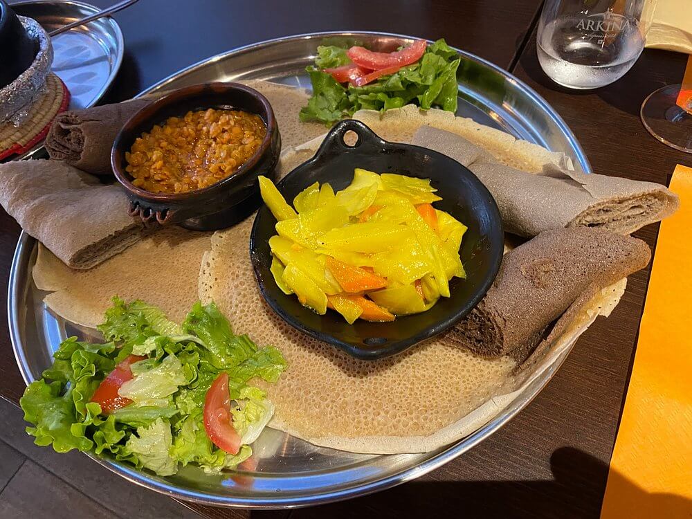 Traditional vegetarian and meat Eritrean injera platter at Hidmona Restaurant Geneva