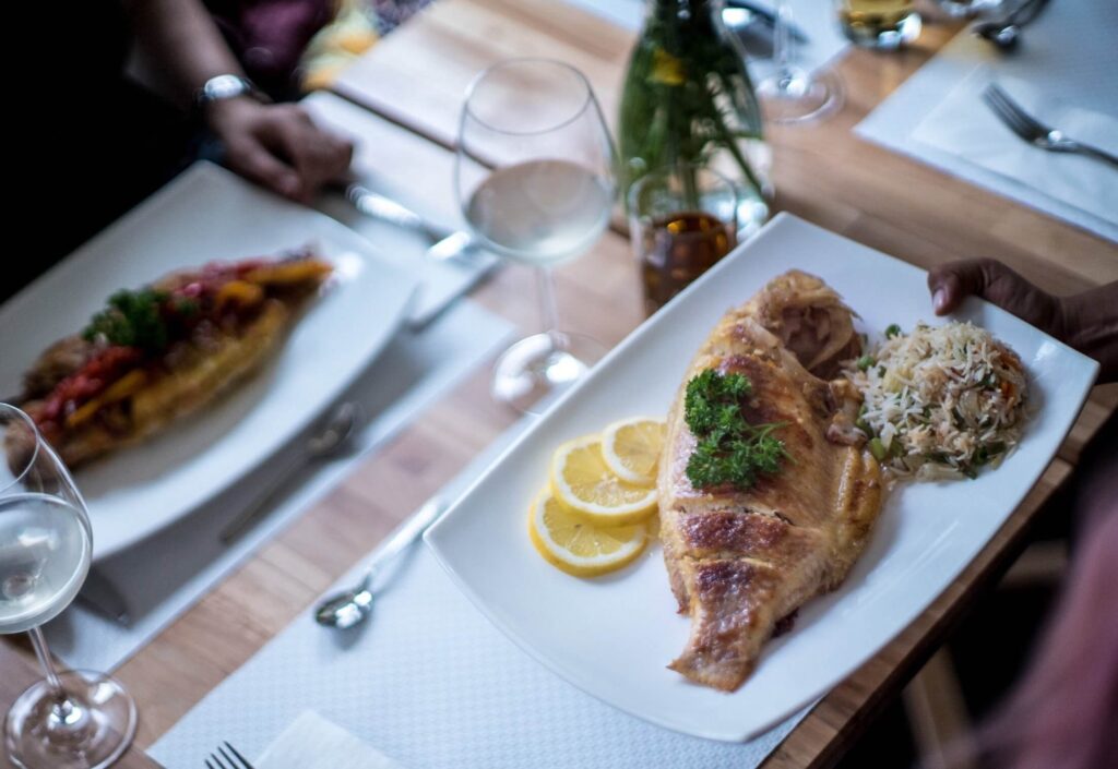 Grilled fish served with rice and fresh garnishes, showcasing authentic Nigerian and West African cuisine at Queen Idia Authentic Nigerian Restaurant Zurich
